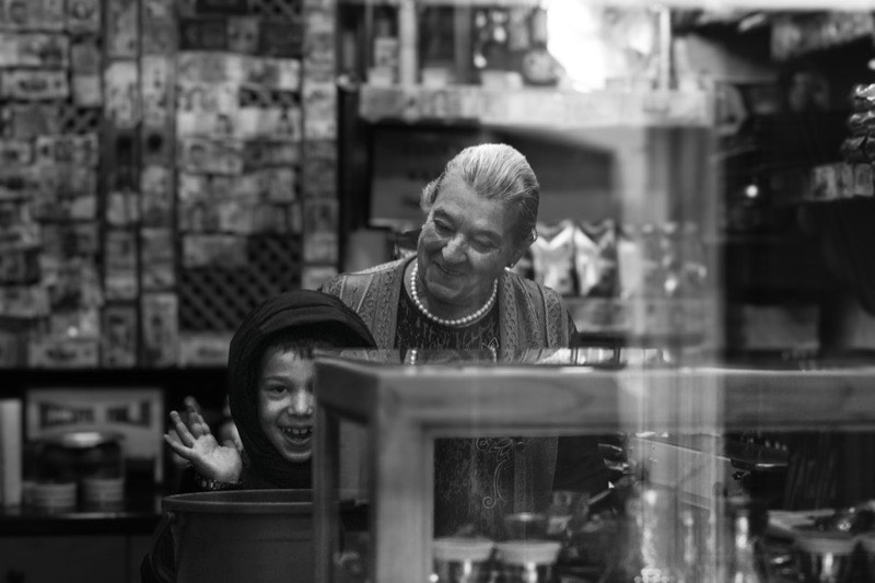 A grandmother and a laughing child behind a shop counter