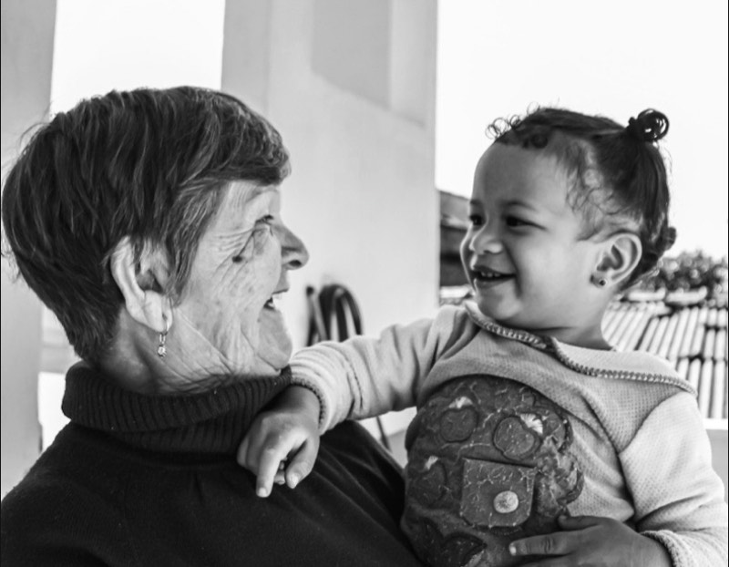 A grandmother laughing with a small child in her arms